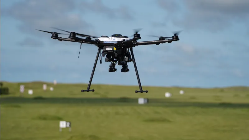 A drone flying over marker signs on a green field.