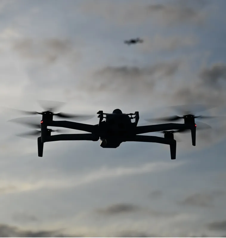 Two Skydio X10D drones fly over LoanDepot Park. In the foreground, the first drone stands out in contrast to the evening sky. In the background: a second Skydio X10 drone can be seen in the distance.