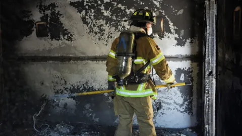 Firefighter in front of burned building