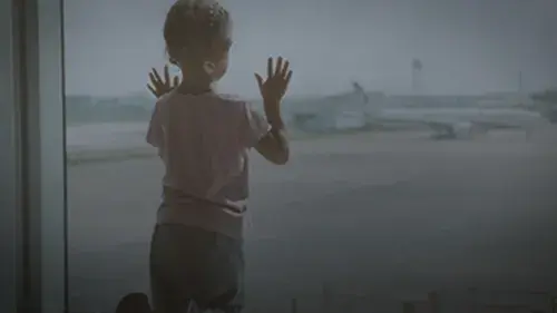 Child watching planes from airport window