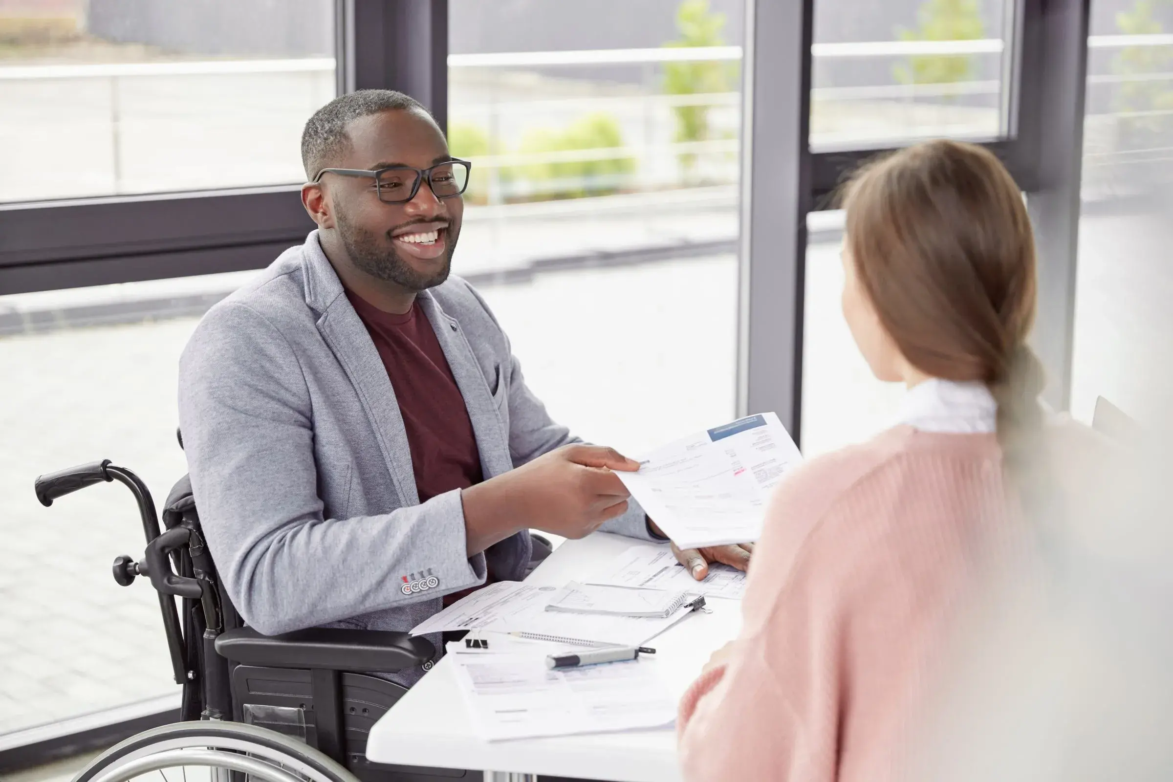 Male sits at workplace in wheelchair with female coworker